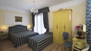 A hotel room with two beds, a wardrobe, a chair, a desk, and a chandelier. - Hotel Villa Edera (Venice)