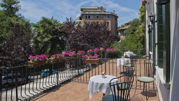 A terrace with outdoor seating, a view of a historic building, and a clear sky. - Hotel Villa Edera (Venice)