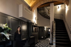 A hotel lobby with a reception desk, a staircase, and a patterned floor. - Hotel La Gioconda (Florence)