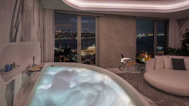 Een moderne badkamer met een jacuzzi, een bank en uitzicht op de stad.