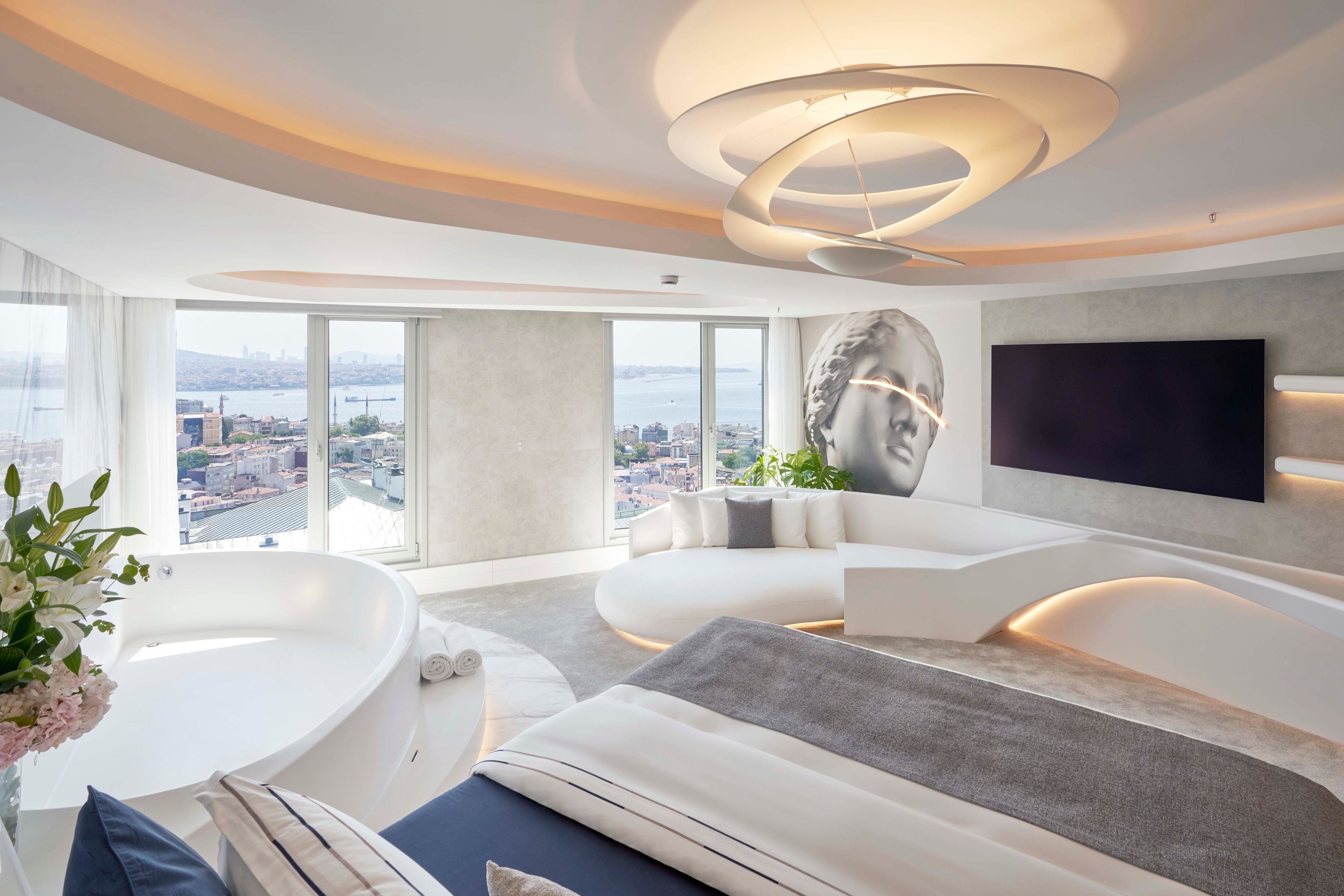A modern living room with a large window, a bathtub, and a flat-screen TV.
