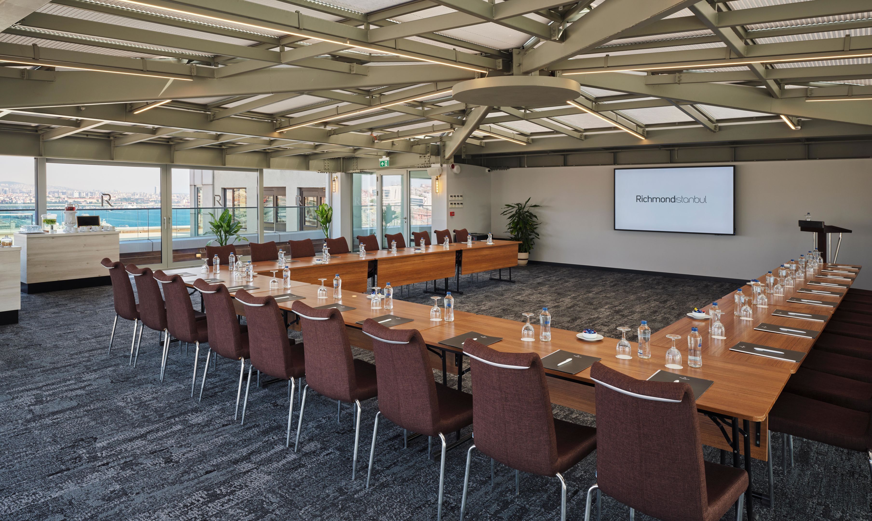 A conference room with a long table, chairs, and a projector screen displaying "RichmondInternational".