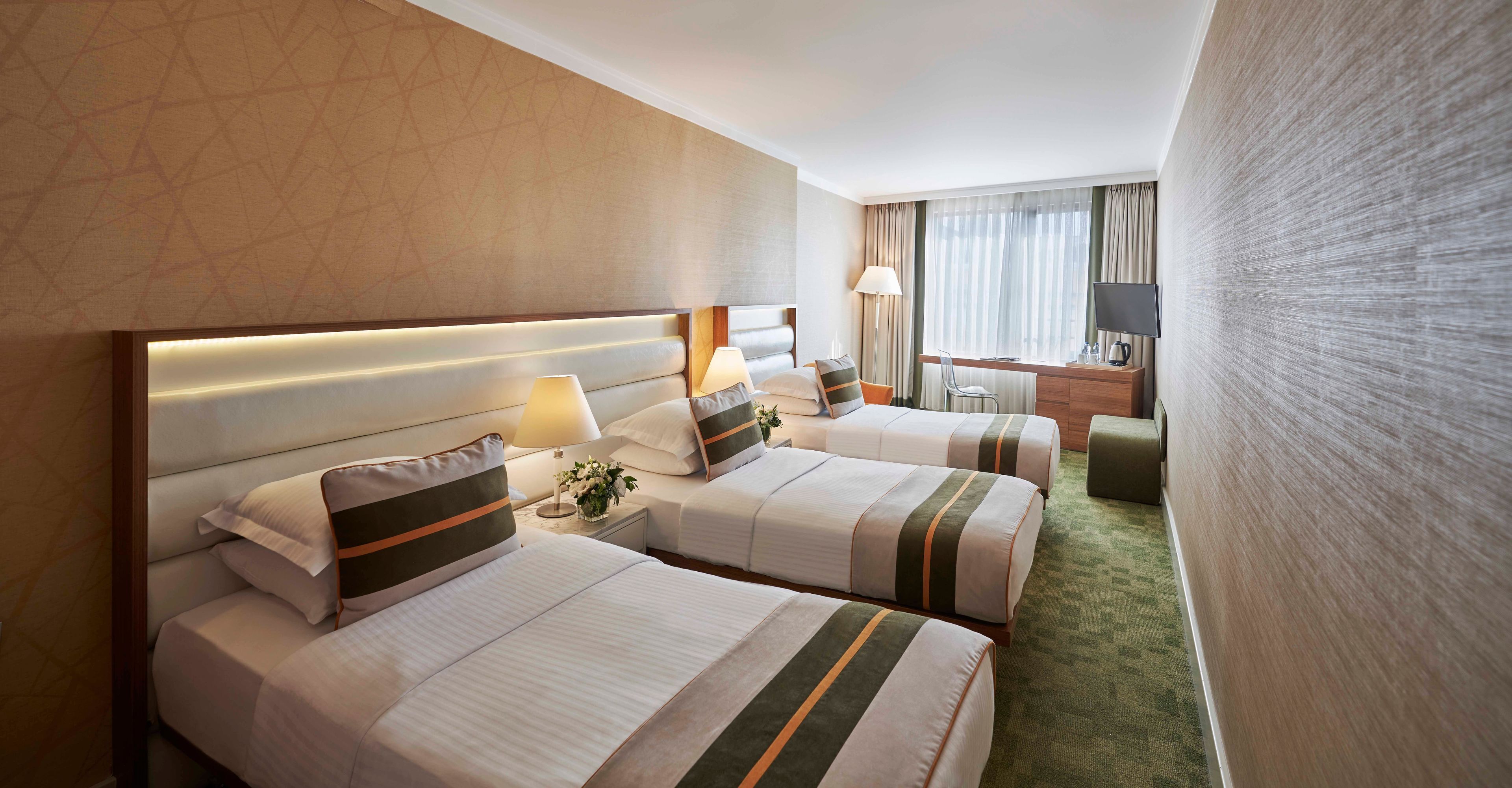 Ein Hotelzimmer mit zwei Betten, einem Schreibtisch, einem Stuhl, einem Fernseher und einer Lampe.
