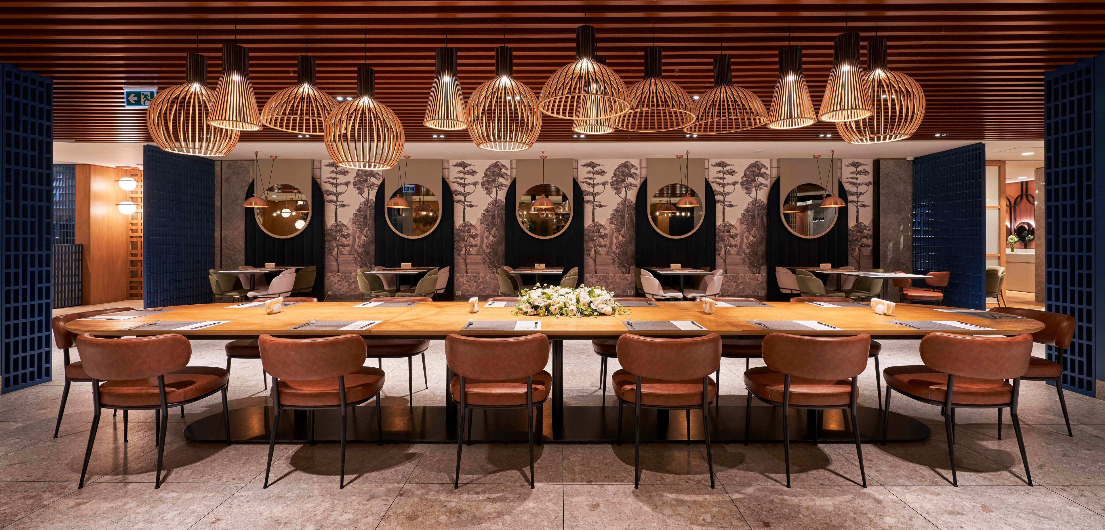 A conference room with a long table, multiple chairs, and hanging pendant lights.