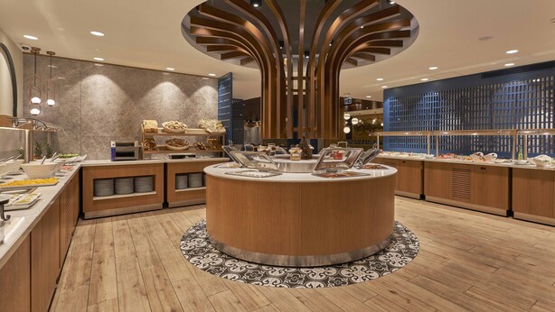A modern buffet area with a central island, multiple serving stations, and a decorative ceiling feature. - Richmond Istanbul (Istanbul)