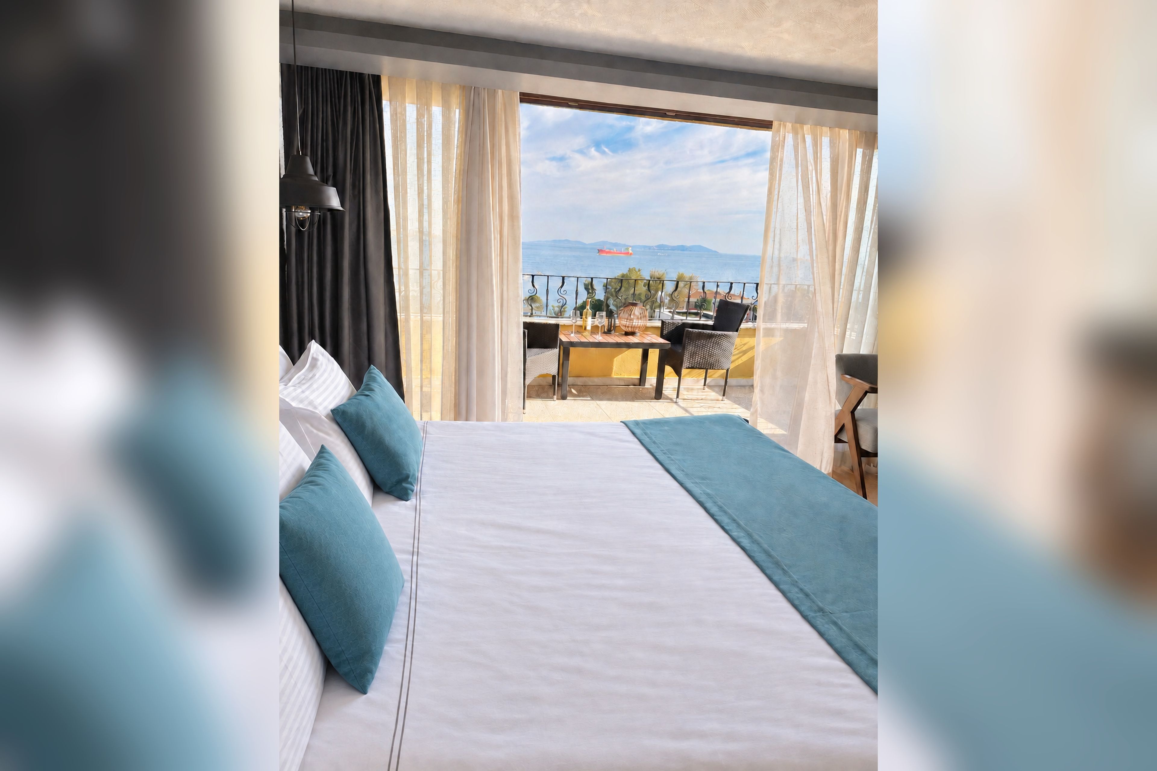 Et hotelværelse med en stor seng, en balkon med bord og stole, og havudsigt.