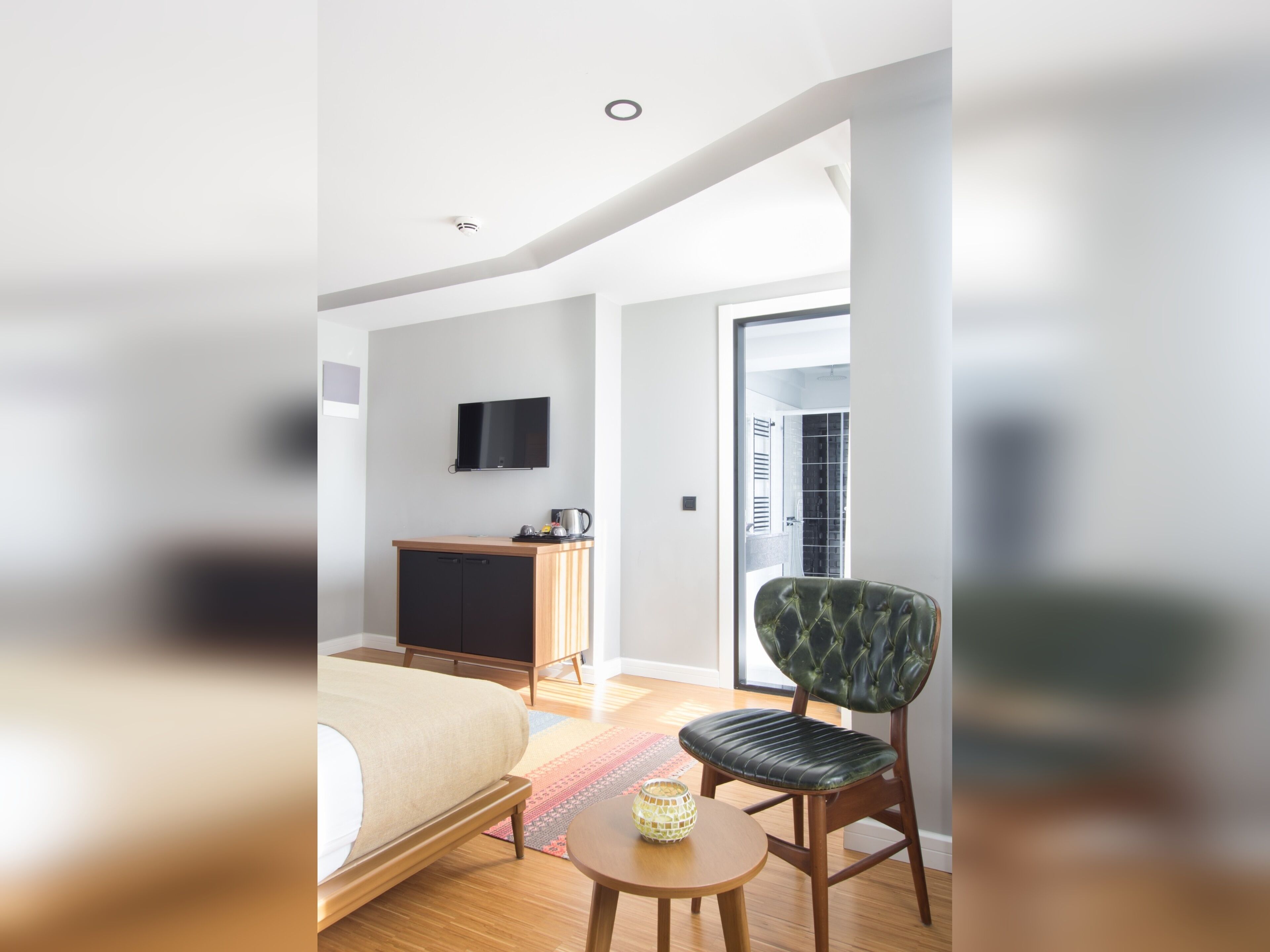 A modern hotel room with a bed, a television, a desk, and a chair.