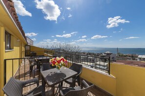 A balcony with wicker furniture and a vase of flowers, overlooking a coastal view. - Arena Hotel - Special Class (Istanbul)