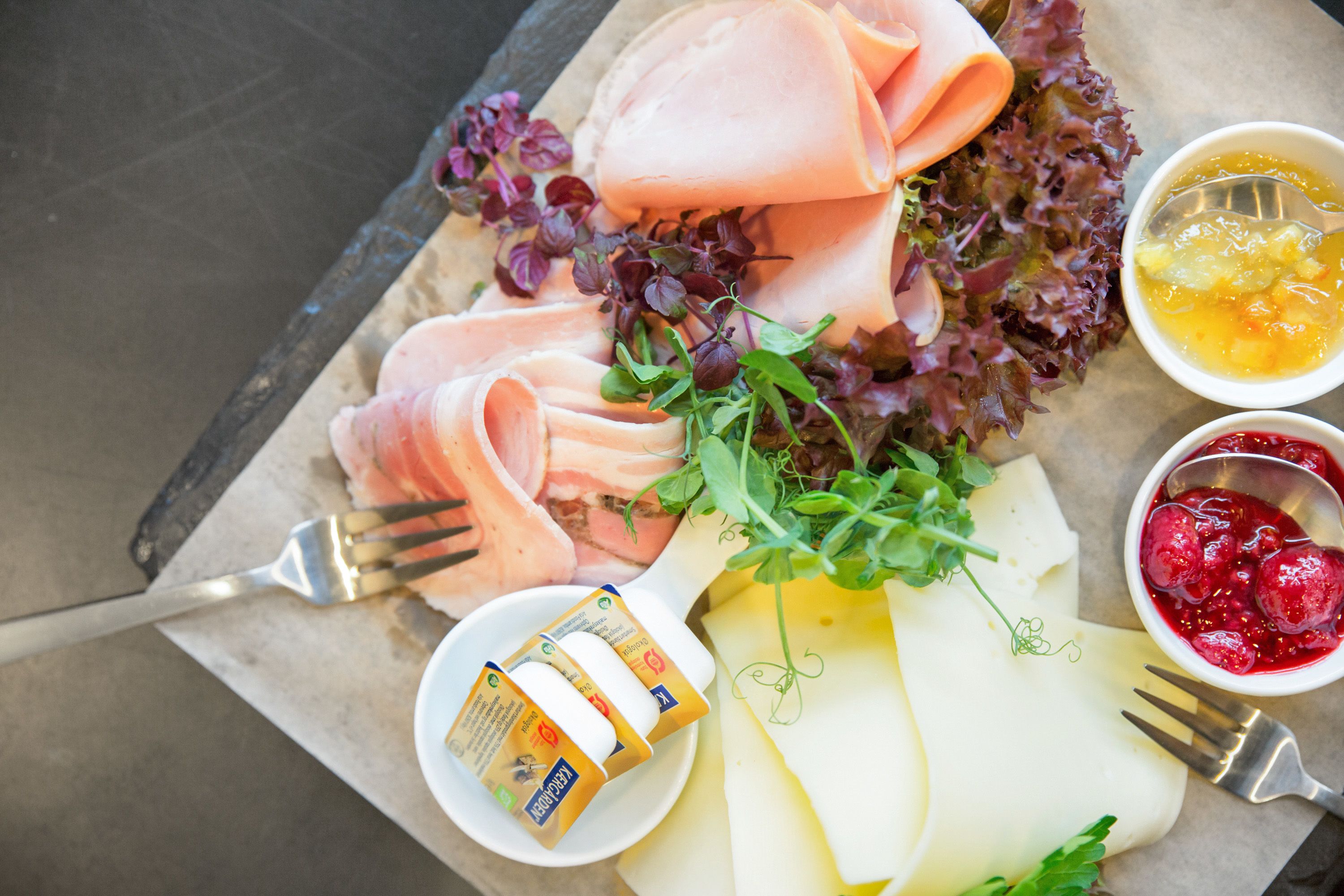 Una tabla de embutidos con carnes frías, queso y diferentes acompañamientos.
