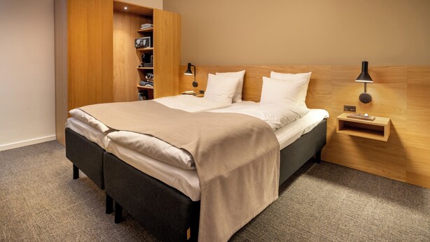 Un dormitorio moderno con cama, mesitas de noche, un armario y una mesita auxiliar.