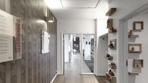 Un pasillo con papel tapiz estampado, suelo de madera y estantes empotrados con objetos decorativos.