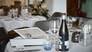Una mesa de comedor dispuesta con copas de vino, una botella, un menú y un candelabro.