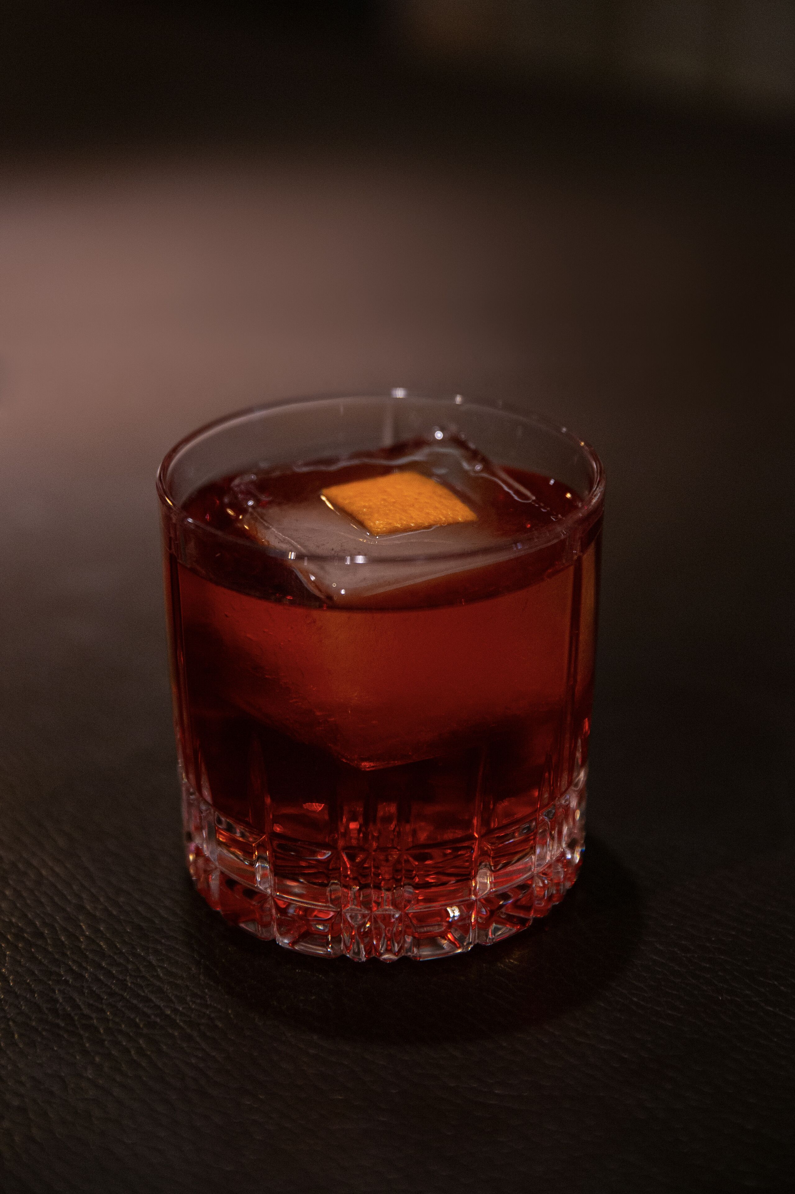 Un vaso transparente con un cubo en su interior, sobre una superficie oscura.