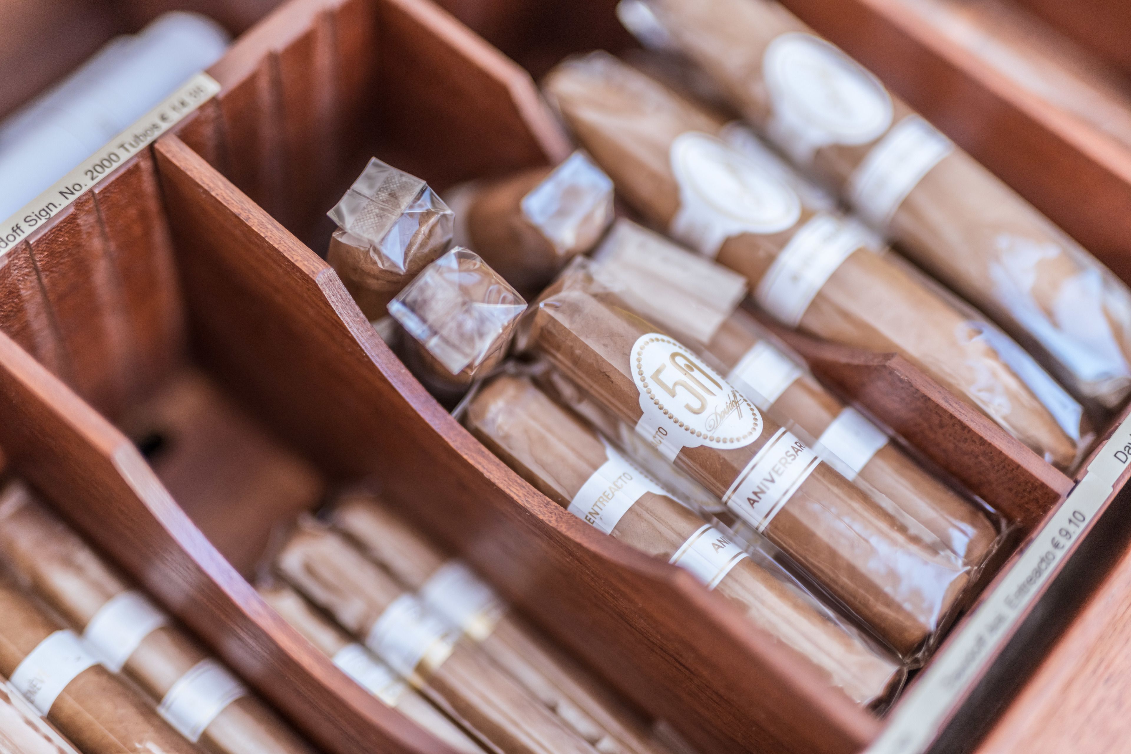 Une boîte en bois contenant plusieurs cigares, chacun étant muni d’une étiquette.