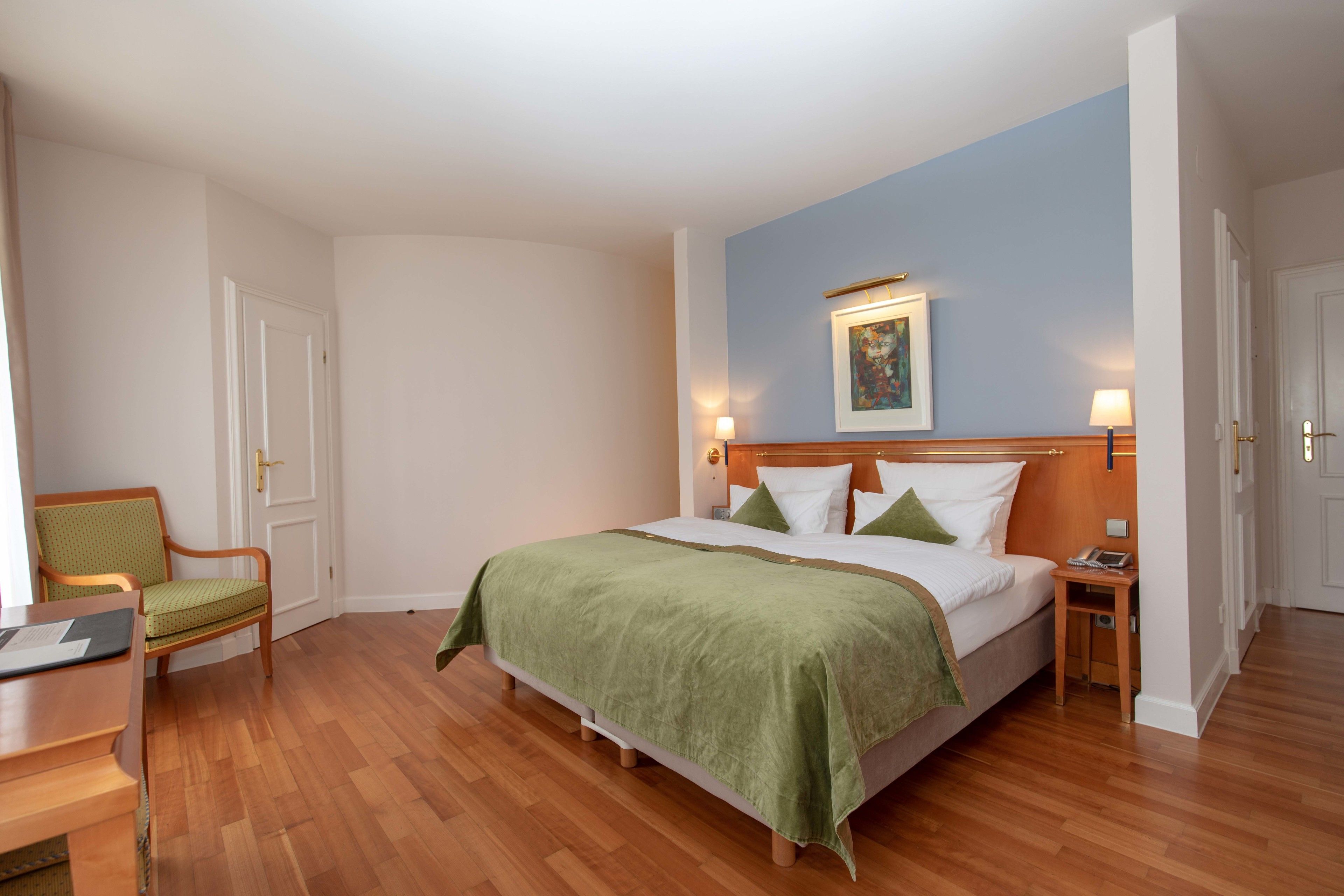 Una habitación de hotel con una cama grande, una silla, una mesita de noche y un escritorio.