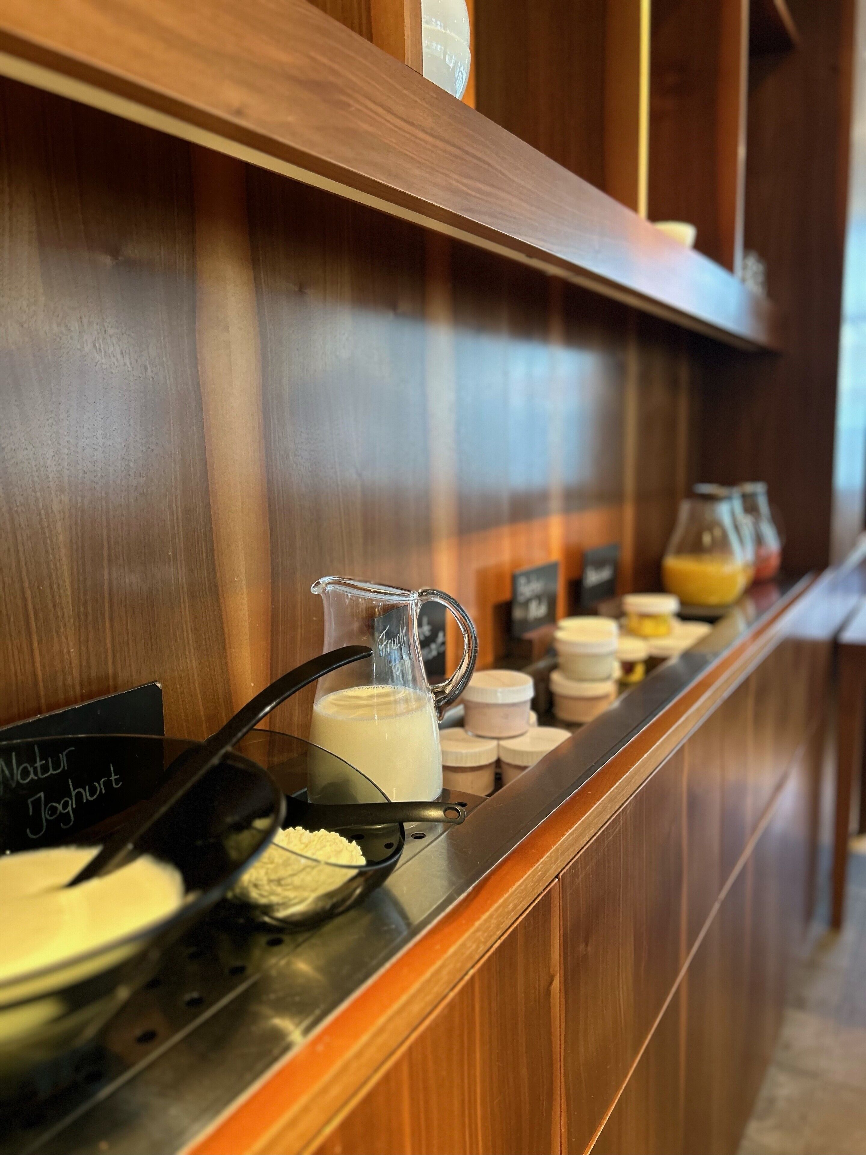 Mostrador de buffet con diversos alimentos y una jarra de leche.