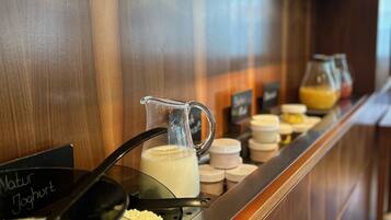 Mostrador de buffet con diversos alimentos y una jarra de leche.