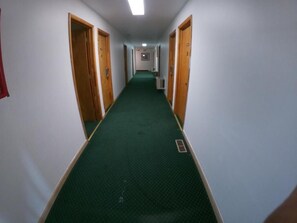 A corridor with carpeted flooring, wooden doors, and a light fixture on the ceiling. - Budget Inn Clearfield (Clearfield)