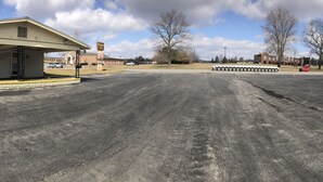 A parking lot with a Farm Table Restaurant sign, a Barnyard Inn sign, and a building with a green roof. - Budget Inn Clearfield (Clearfield)