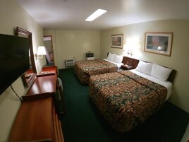 Una habitación de hotel con dos camas, un escritorio, un televisor y un cuadro en la pared.