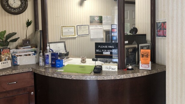 A reception desk with a clock, certificates, and a 'Please ring bell for service' sign. - Budget Inn Clearfield (Clearfield)