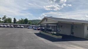 A motel with a covered parking area and several cars parked in front. - Budget Inn Clearfield (Clearfield)