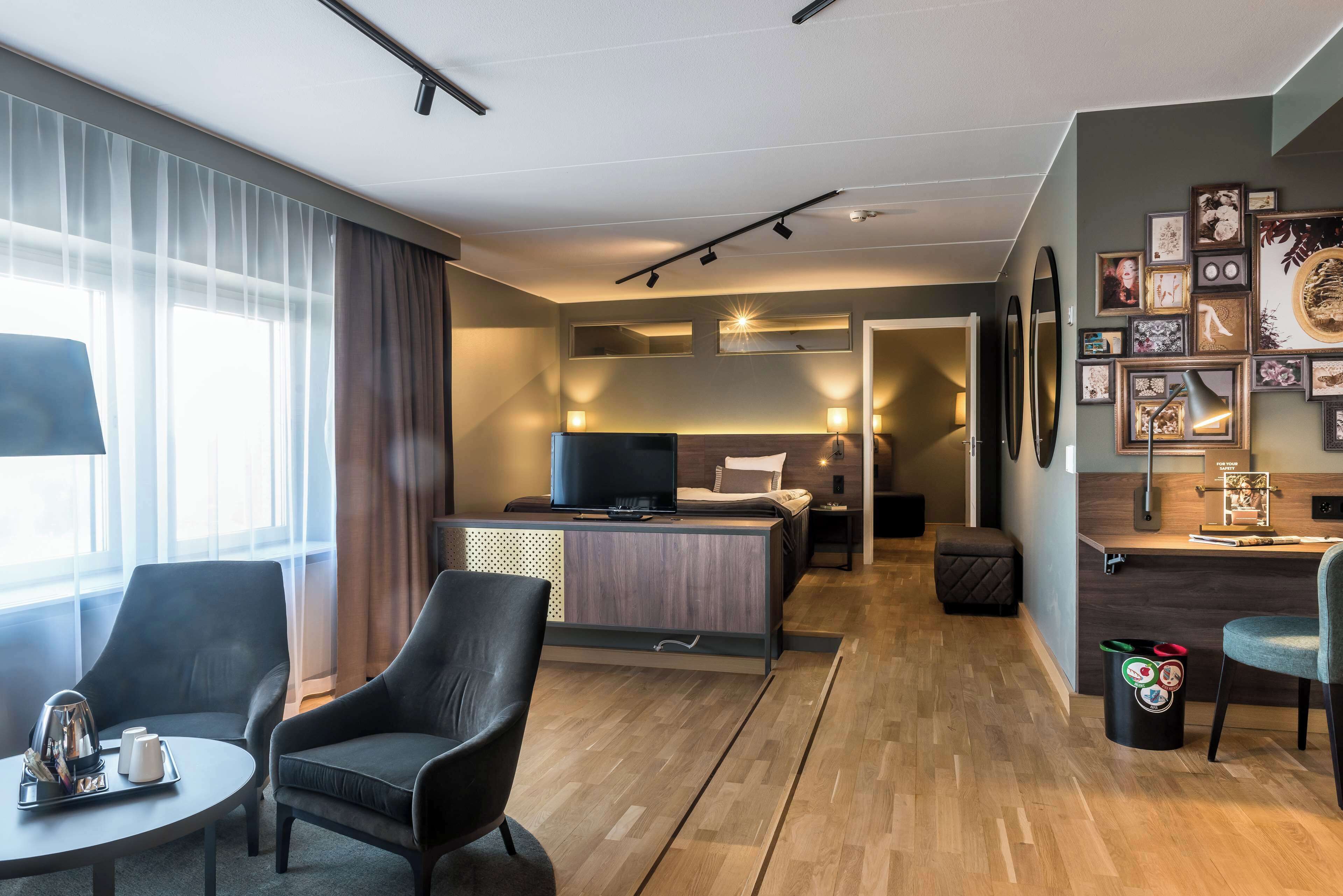 A modern hotel room with a bed, a desk, a chair, and a television.