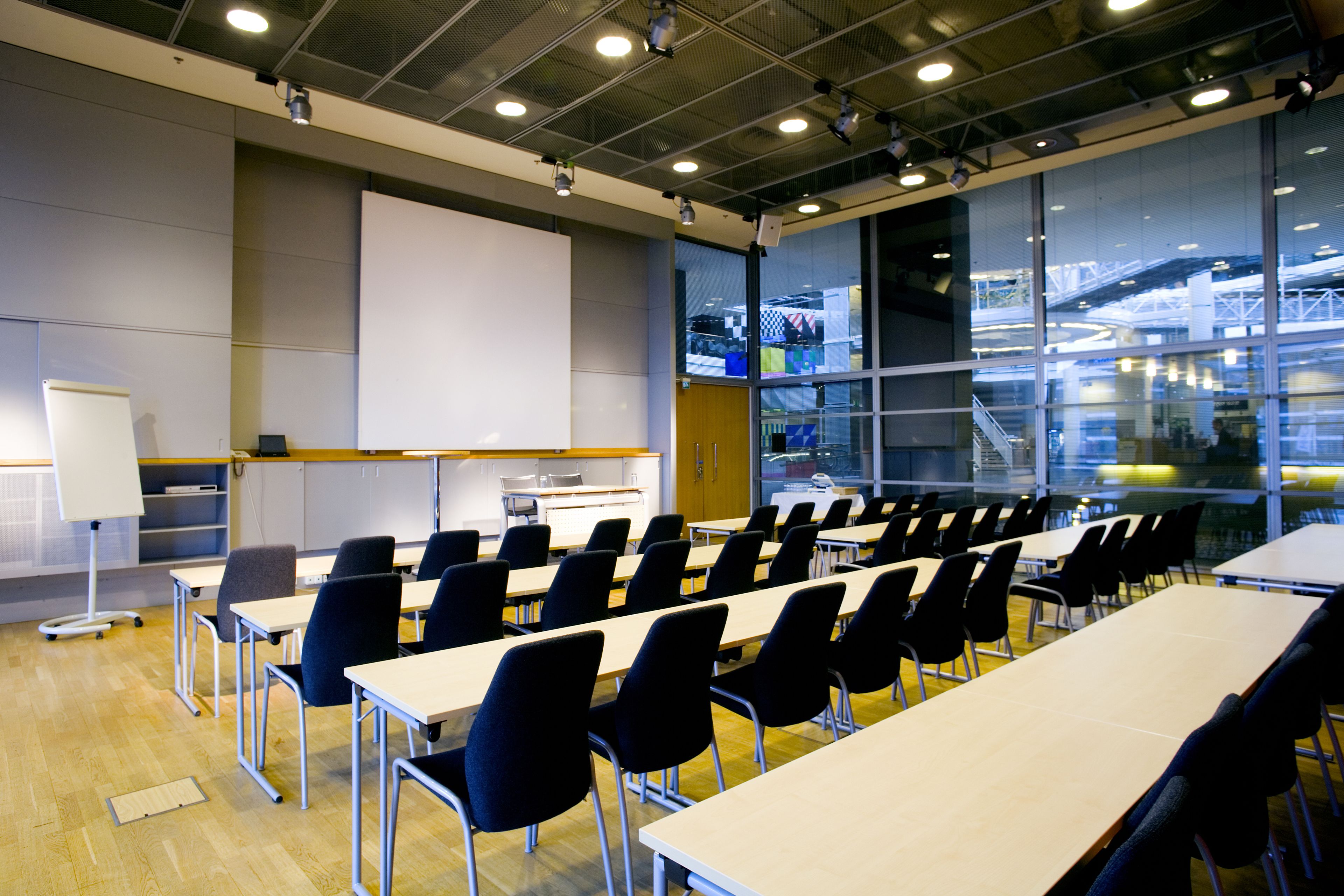 A conference room with rows of tables and chairs, a whiteboard, and a projector.