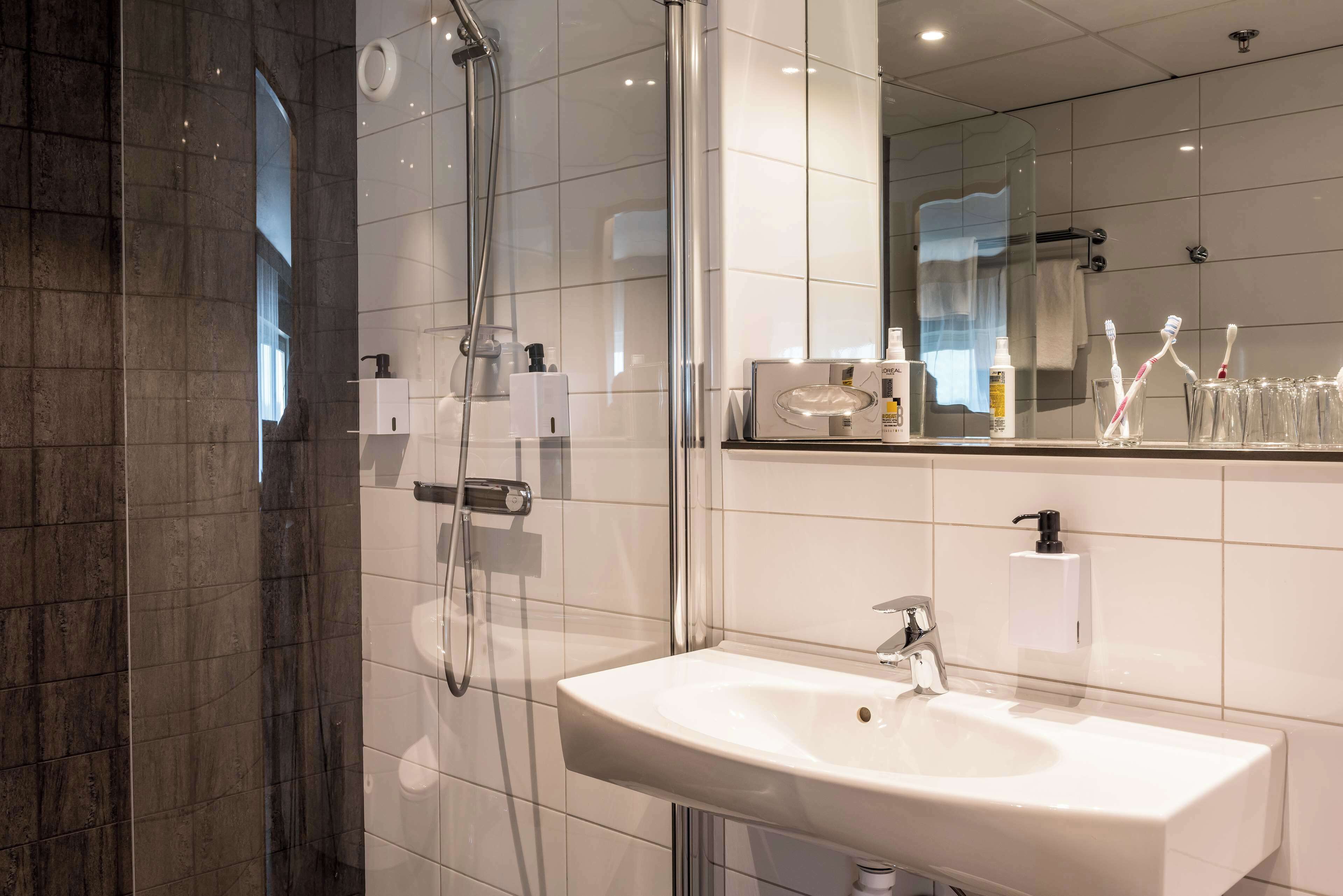 A modern bathroom with a glass-enclosed shower, a white sink, and a large mirror.