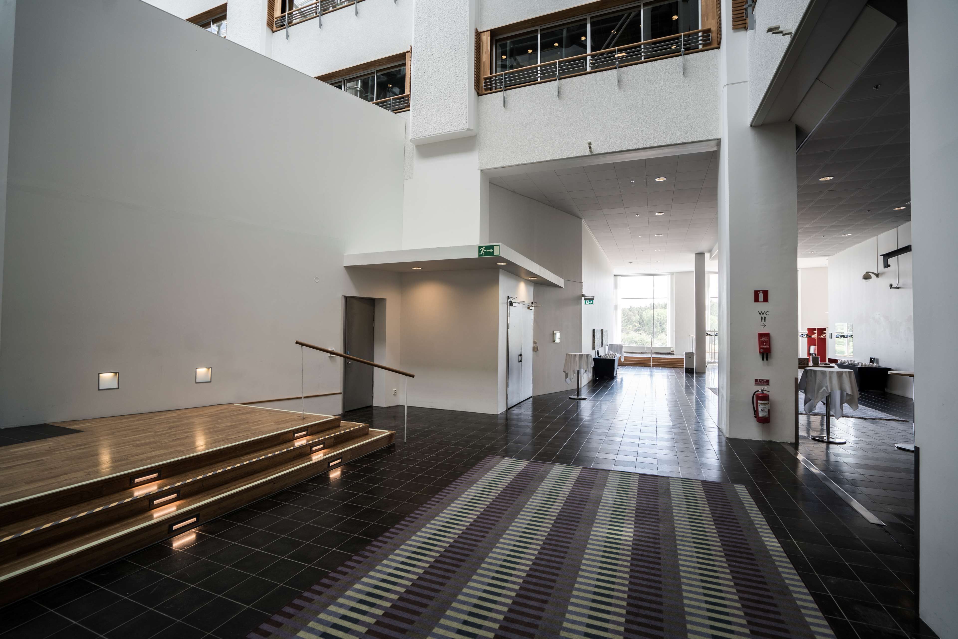 A spacious interior with a staircase, a patterned carpet, and a fire extinguisher on the wall.