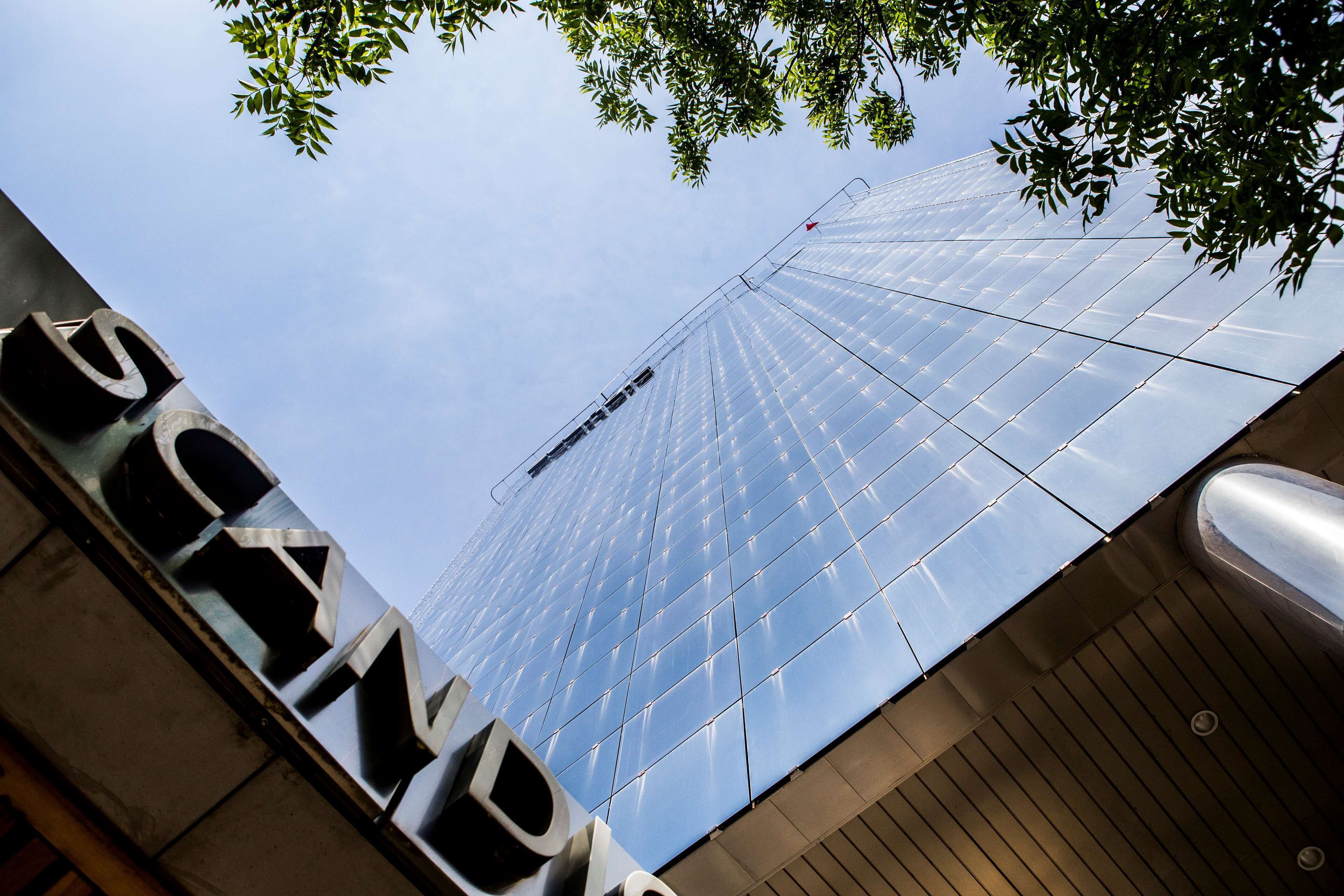 Um edifício moderno com fachada de vidro e uma placa com o nome visível.