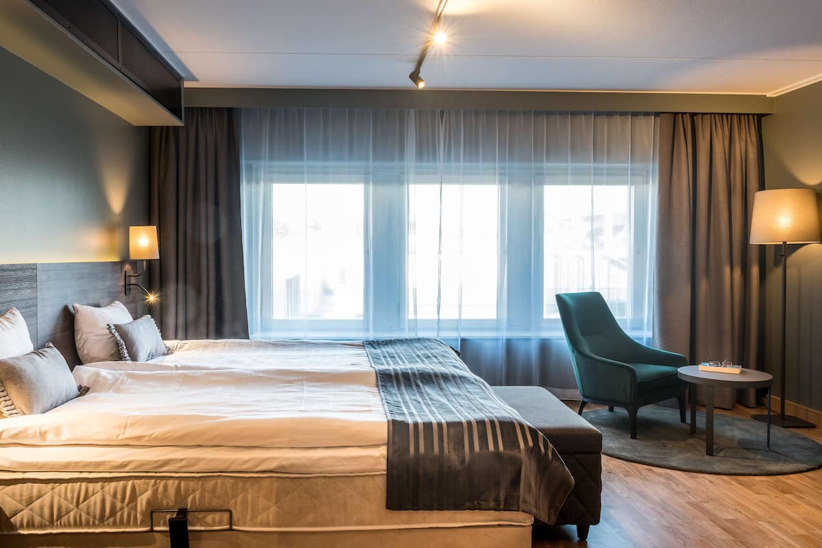 Une chambre d’hôtel moderne avec un grand lit, une chaise et une petite table.