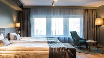 A modern hotel room with a large bed, a chair, and a small table.
