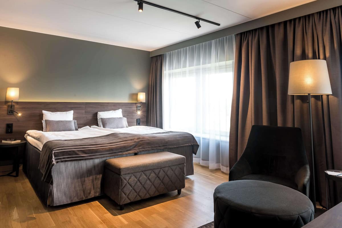 Une chambre d’hôtel moderne dotée d’un grand lit, d’un coin salon et offrant une vue sur l’extérieur.