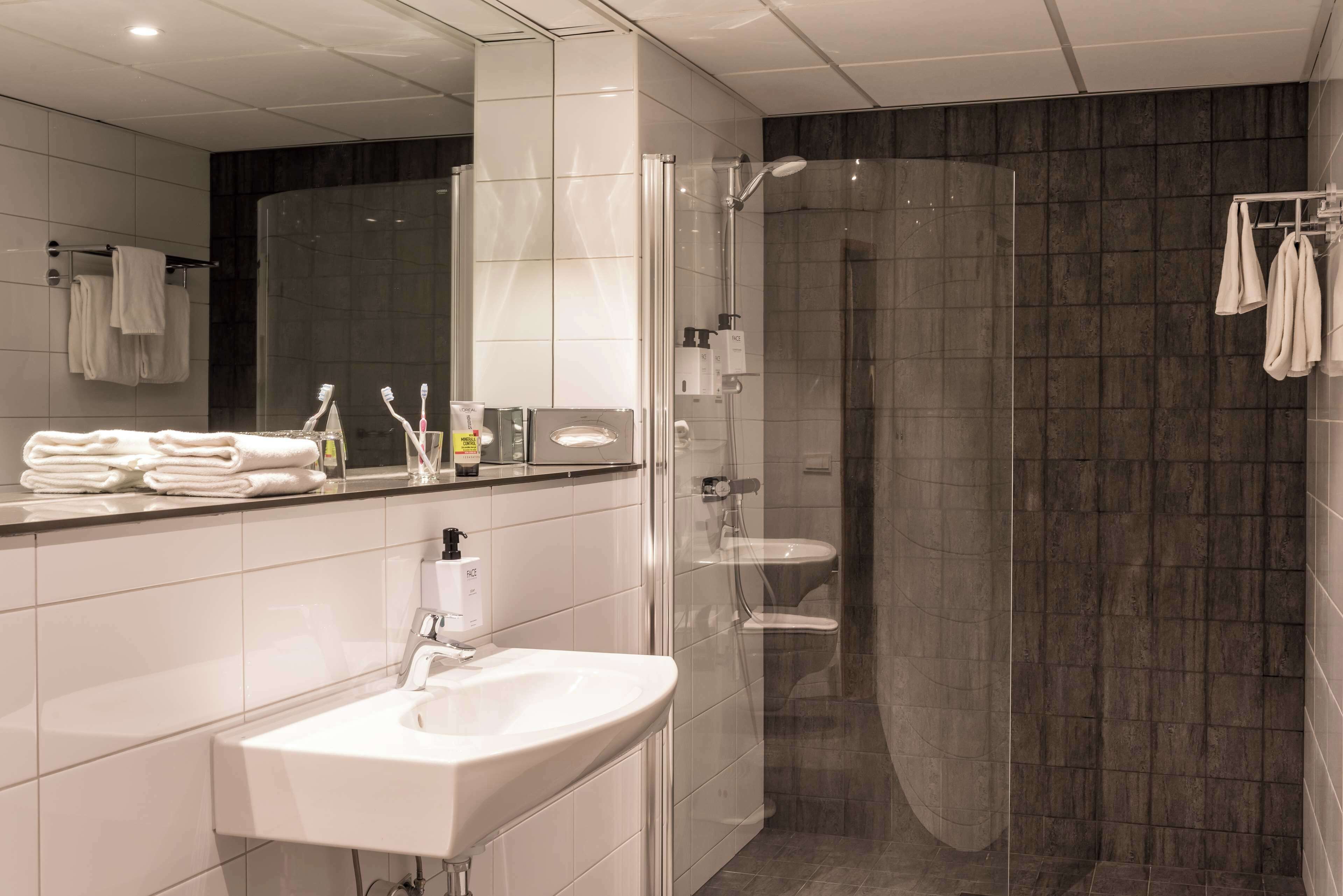 Un baño moderno con ducha de vidrio, un lavabo blanco y un espejo encima.
