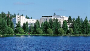 Un hôtel au design moderne, situé près d’un plan d’eau et entouré de verdure.