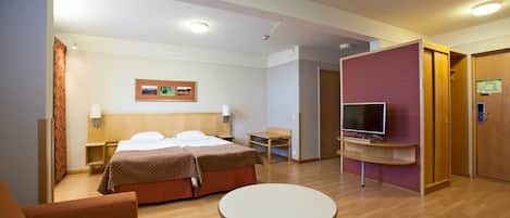 A hotel room with a bed, a TV, a desk, and a chair.