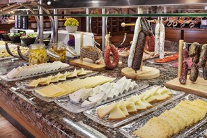 A buffet with various cheeses, cured meats, and pickled vegetables.