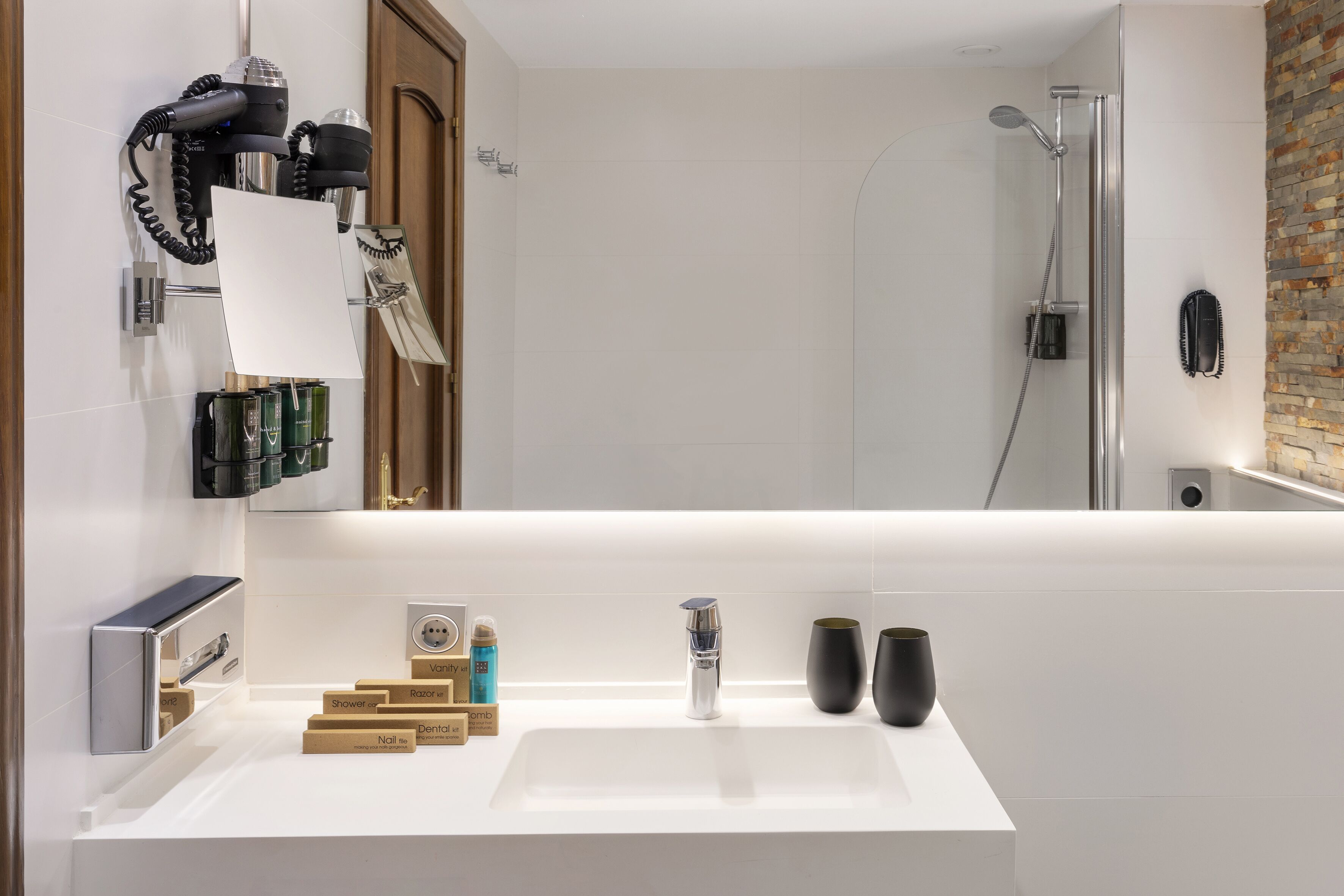 A modern bathroom with a large mirror, a white sink, and a shower area.