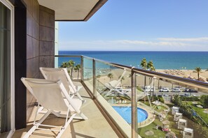 Enjoy the ocean view from this resort's balcony, featuring a pool and lounge chairs.