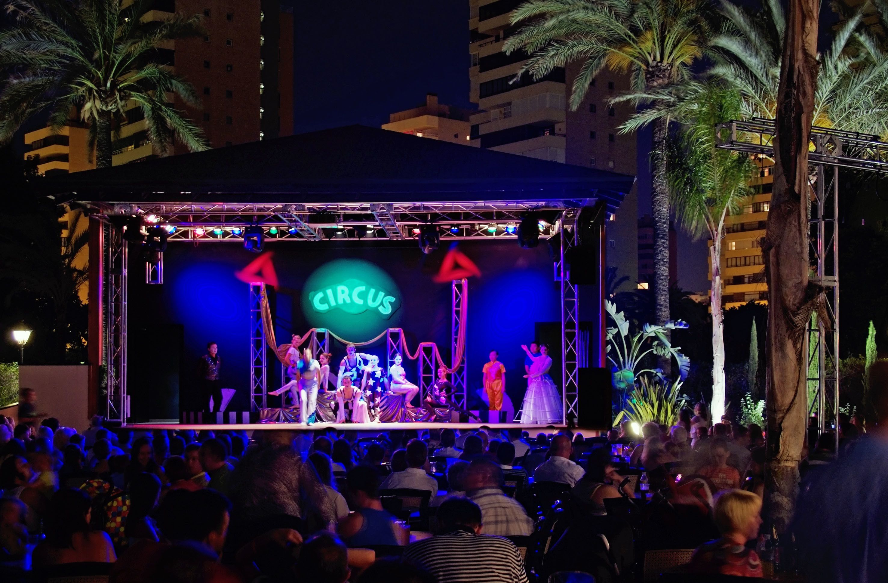 Un escenario de circo con artistas y un público.