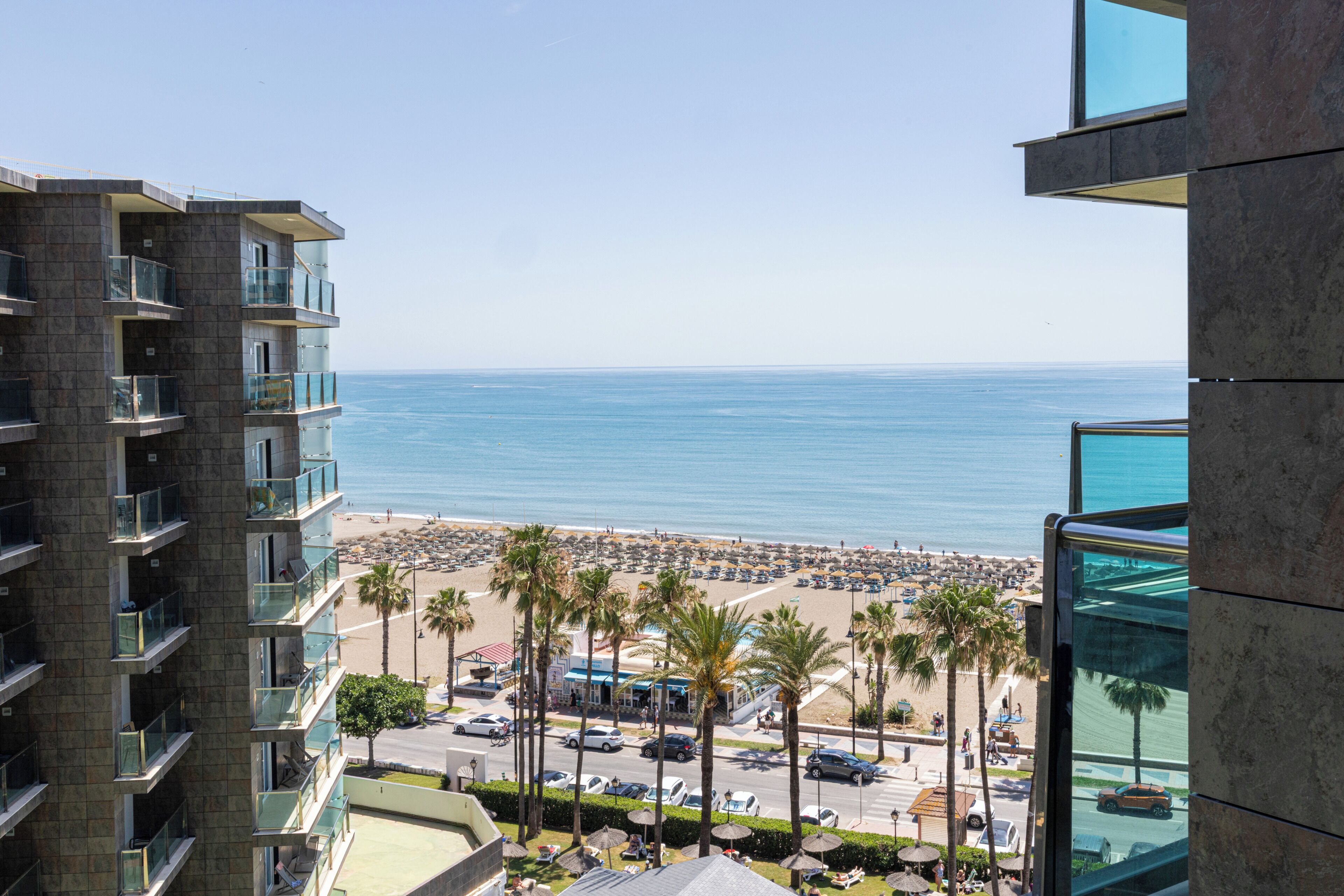 A high-rise hotel with multiple balconies overlooking a beach and ocean.