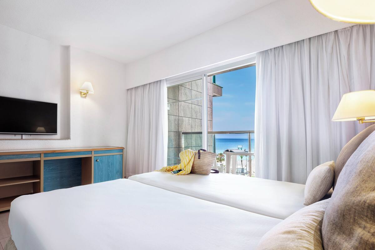 Habitación de hotel con una cama grande, televisión, escritorio y vista al océano.