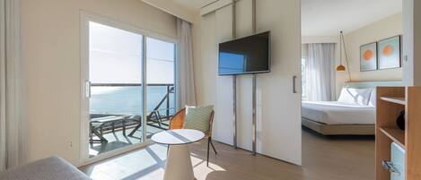 Een moderne hotelkamer met een balkon, een flatscreen televisie, een bed, een kleine tafel en een stoel.