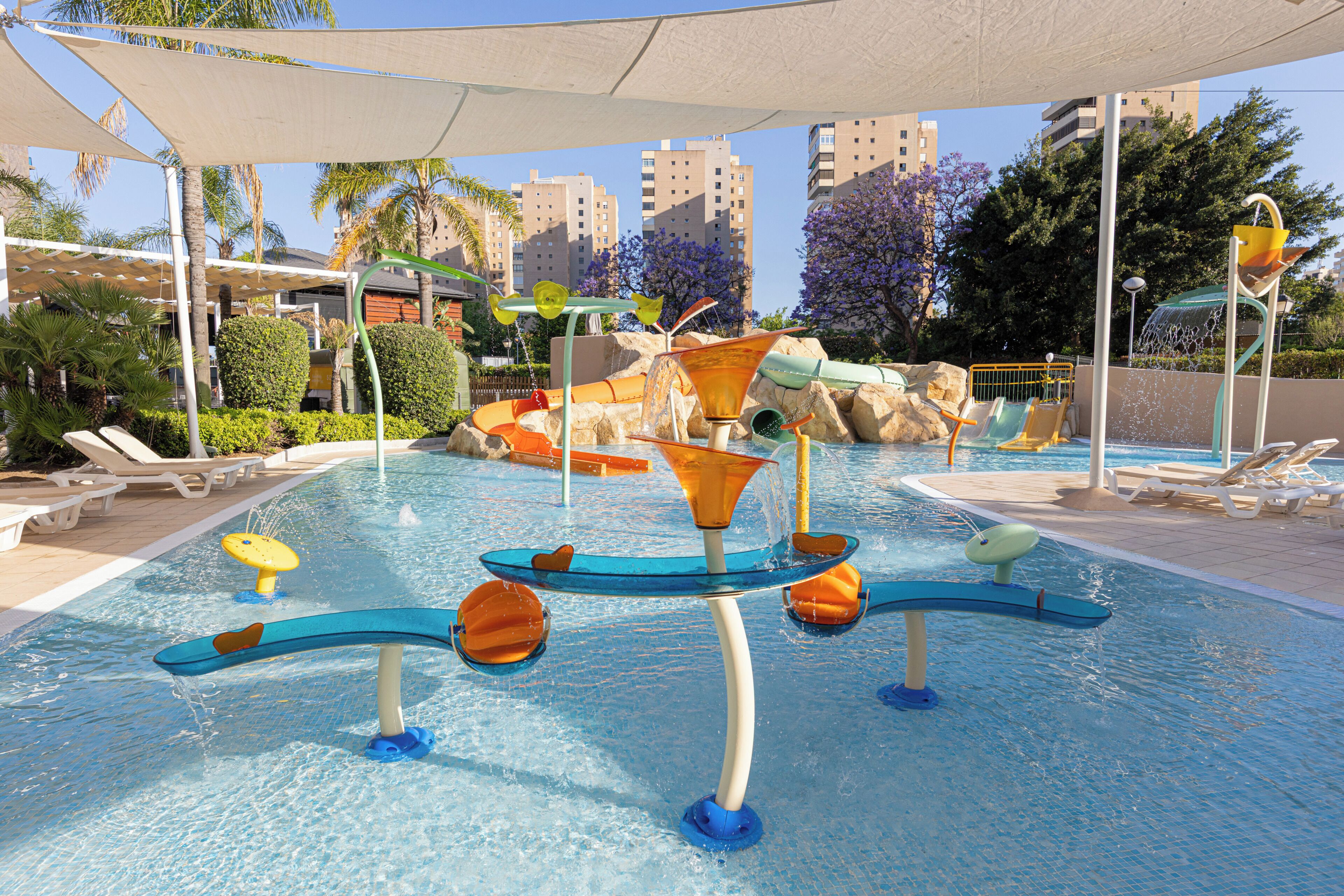 A swimming pool with water slides and a sunshade.