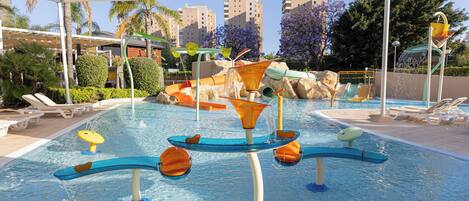 A swimming pool with water slides and a sunshade.