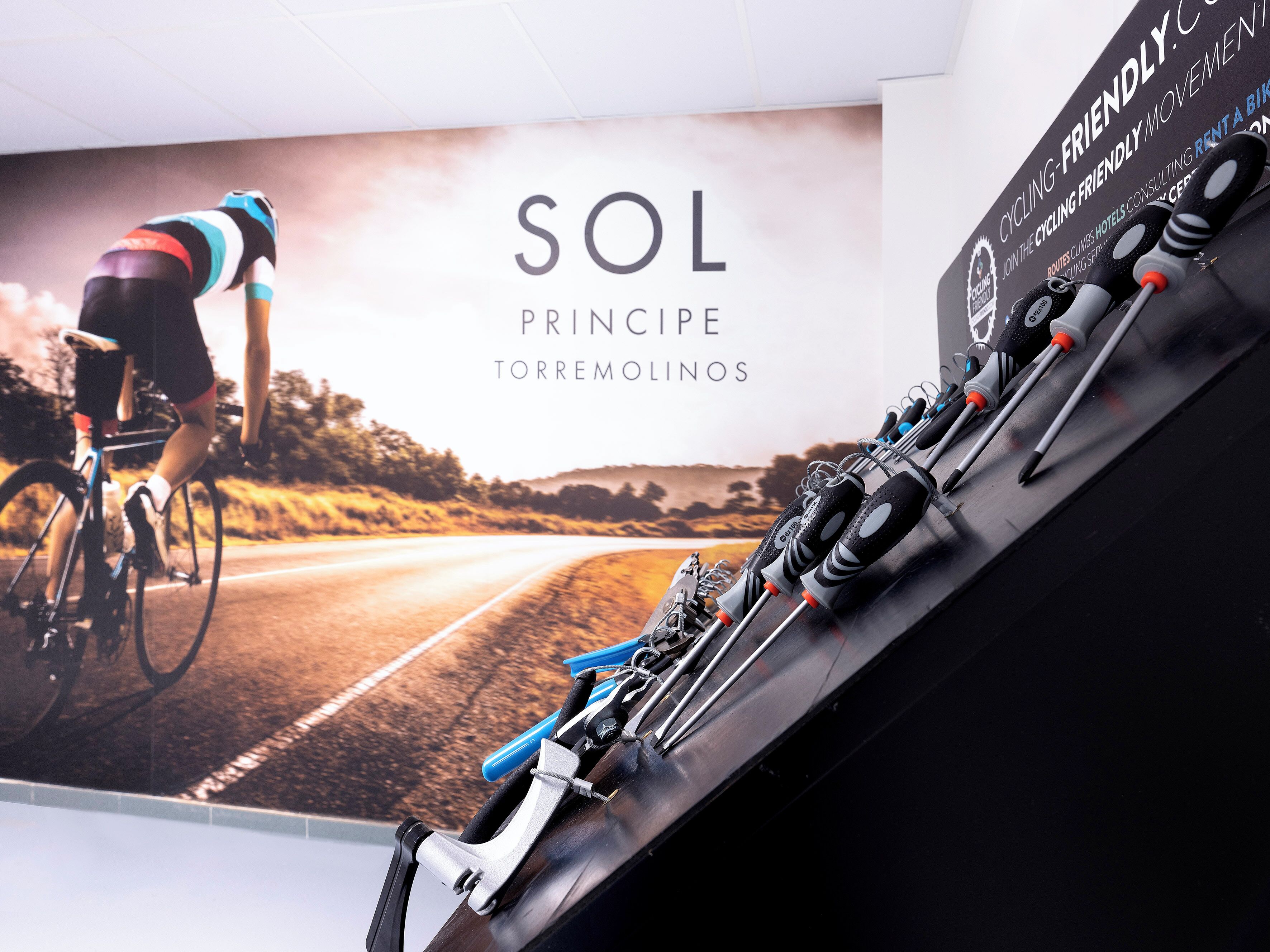 Cartel promocional de Sol Principe Torremolinos que muestra a un ciclista en una carretera, una bicicleta y equipo ciclista.