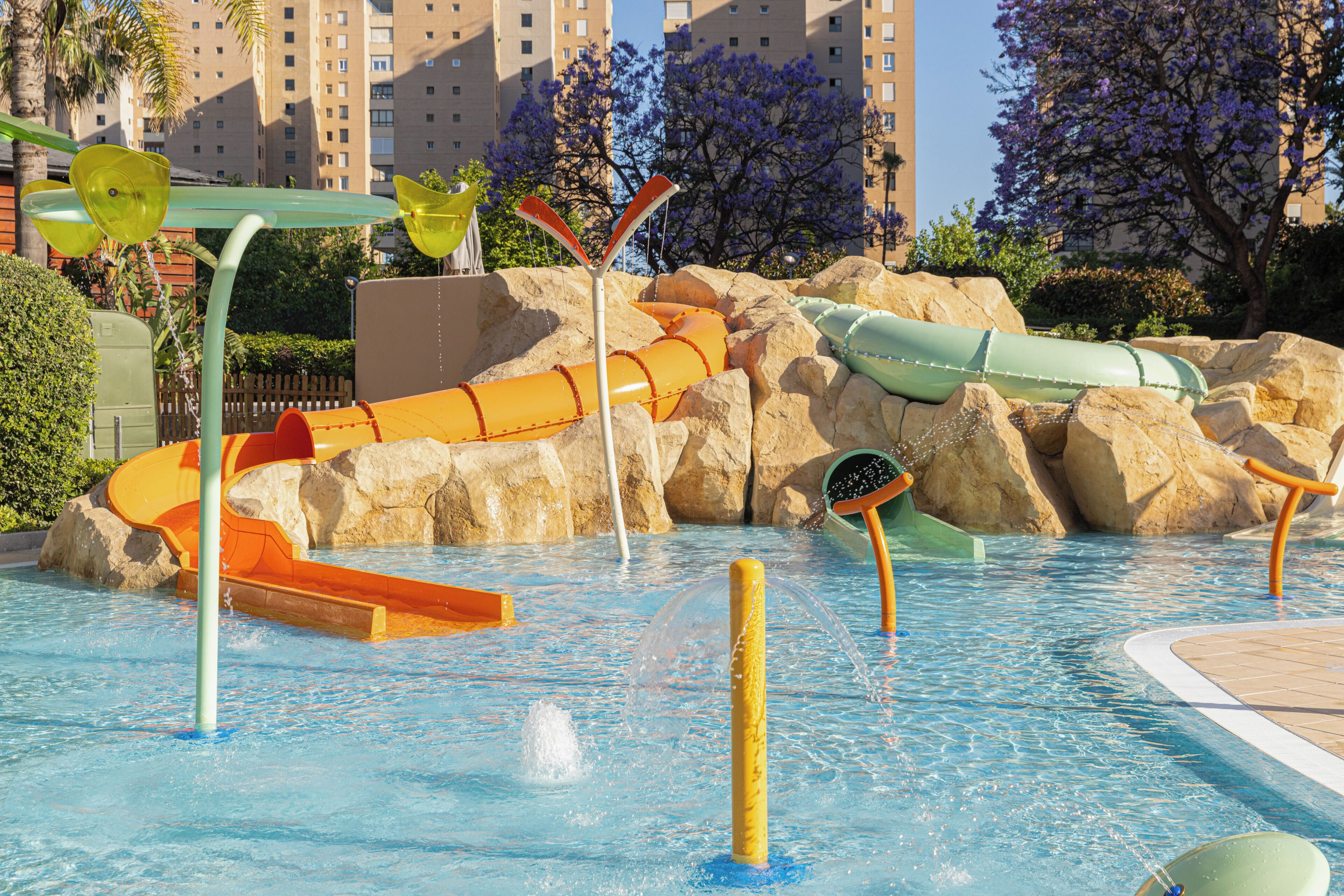 Un parc aquatique avec des toboggans, une piscine et un décor rocheux.