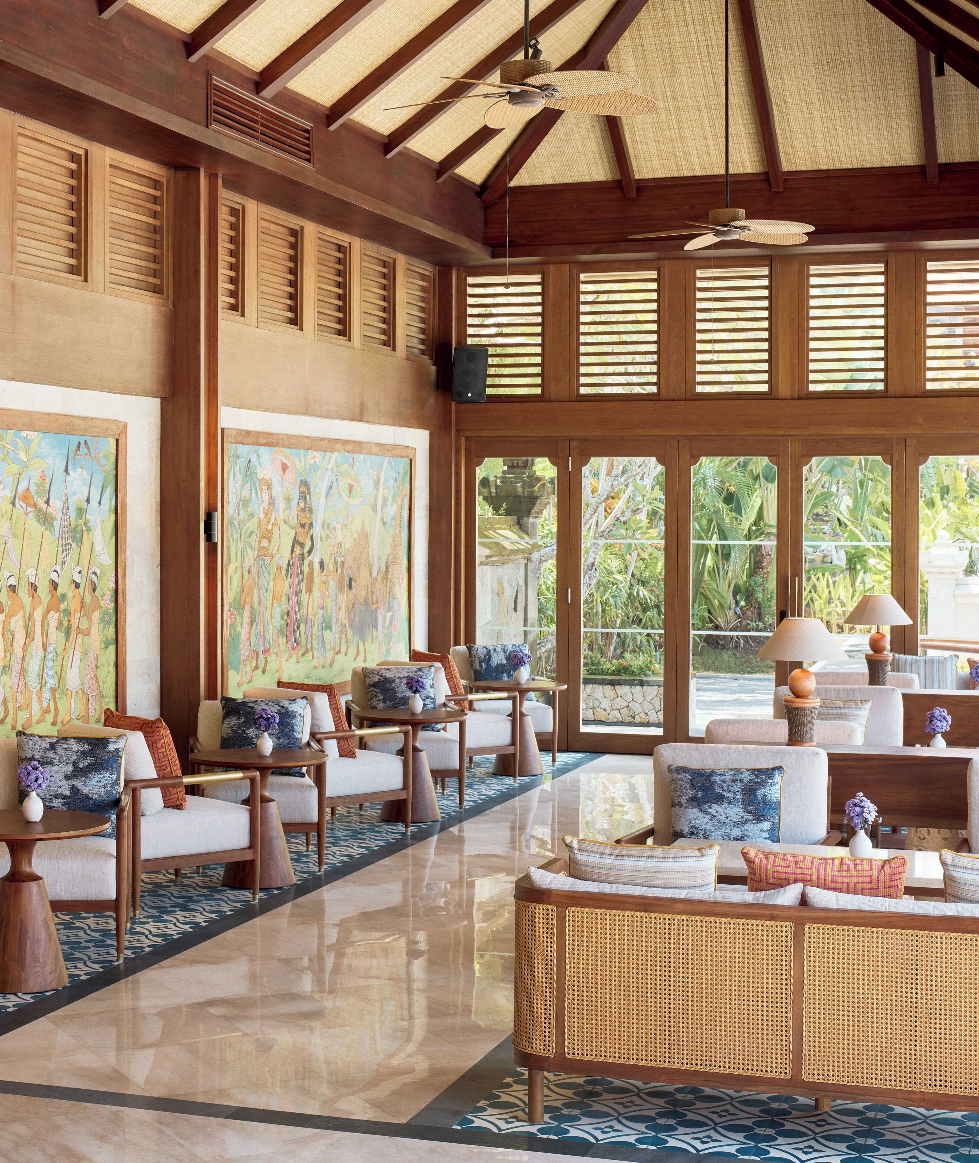 A spacious lobby with a high ceiling, large windows, and a rattan sofa.