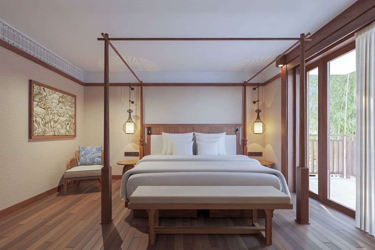 Ein geräumiges Schlafzimmer mit einem großen Bett, Holzboden, einem Baldachin, einem Nachttisch mit Lampe, einem Sessel mit Kissen und einem großen Fenster mit Vorhängen.